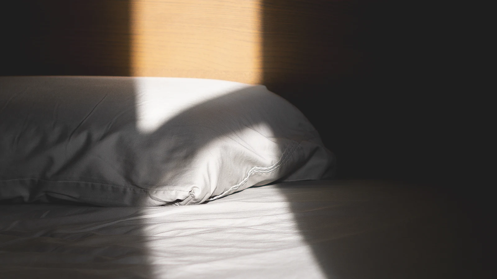 Un haz de sol cruzando una almohada blanca.